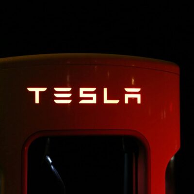 Close-up of a Tesla charging station illuminated at night, showcasing modern automotive technology.